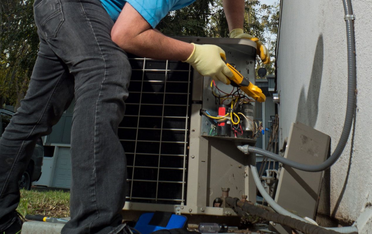 Technician repairing an outdoor air conditioning condenser unit